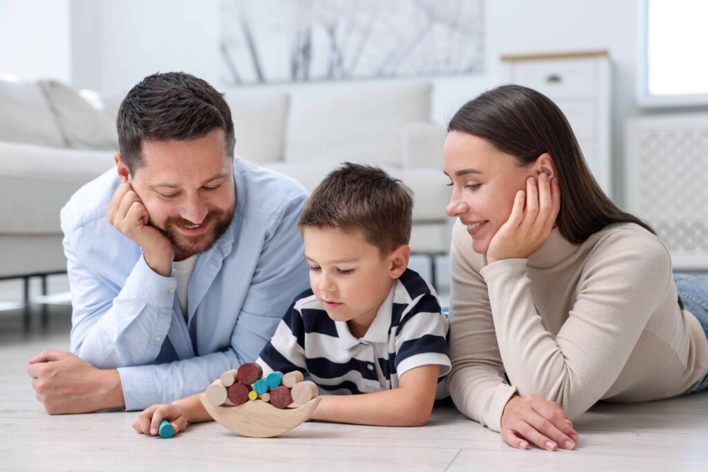 Parents and their son playing with toys on warm floor at home. Heating system